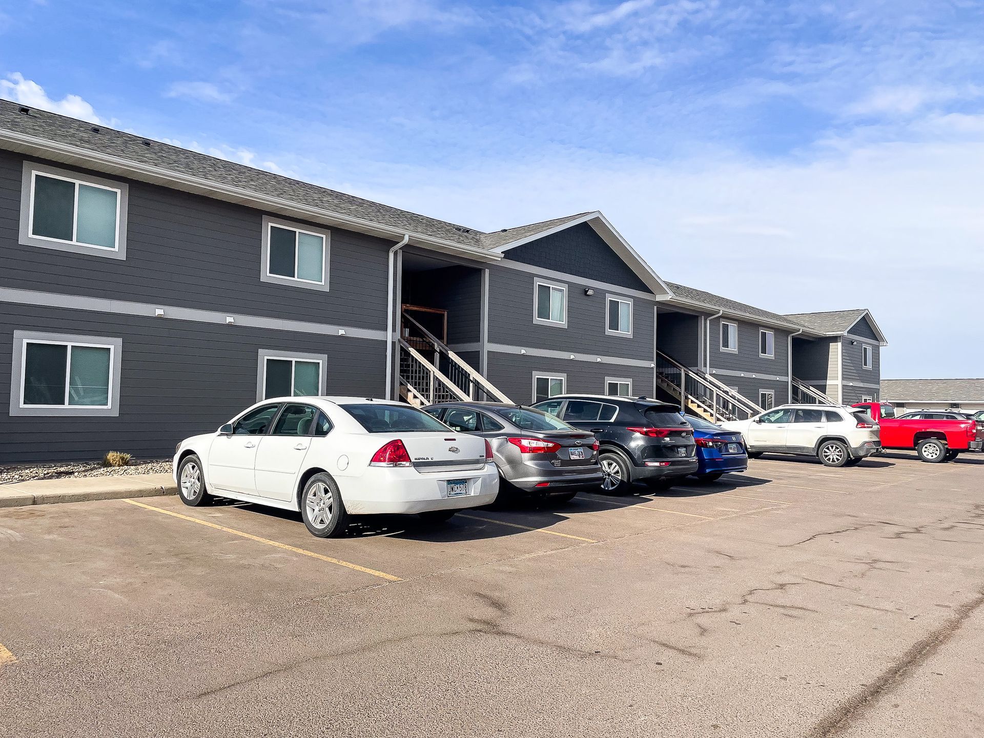 Apartment building with parked cars in a lot on a clear day