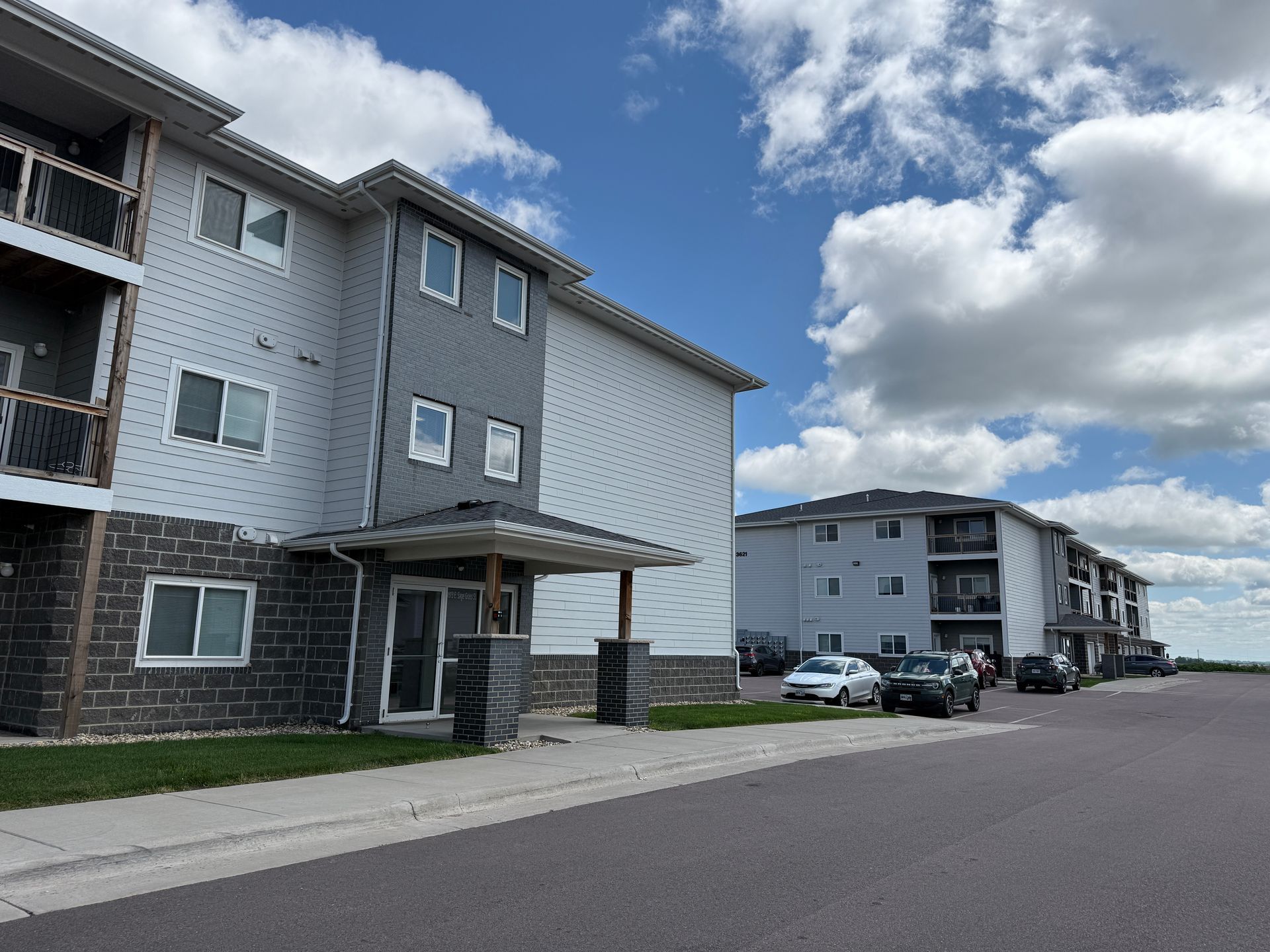 Apartment buildings along a quiet street under a partly cloudy sky.