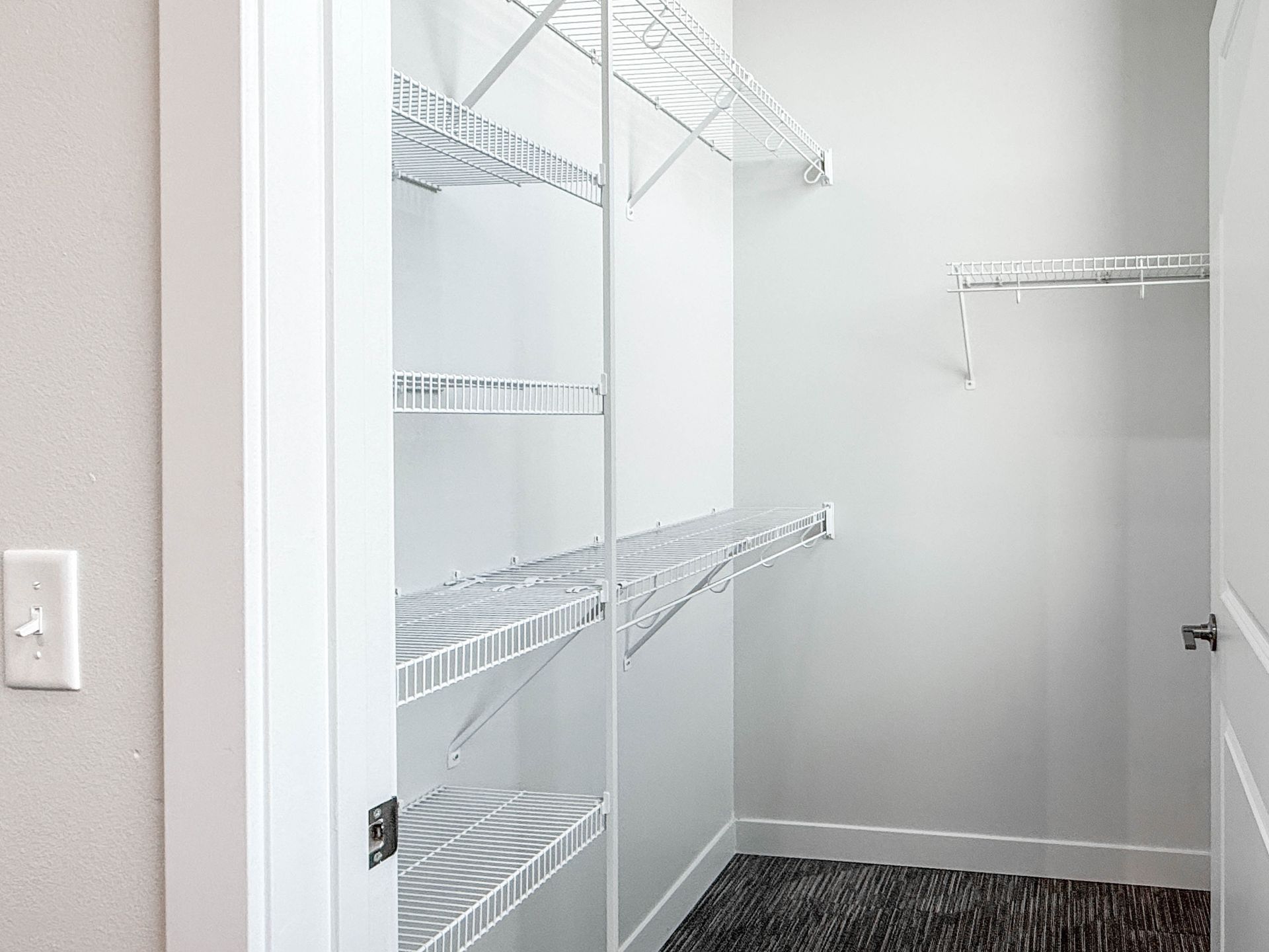Empty white walk-in closet with wire shelves and hanging rods