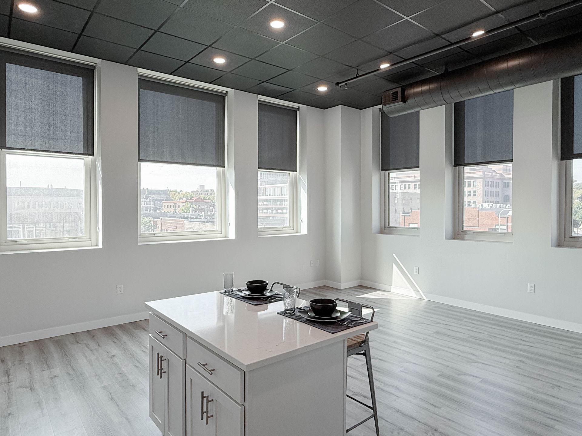 Open-concept apartment with kitchen island, stainless steel appliances, and light wood floors