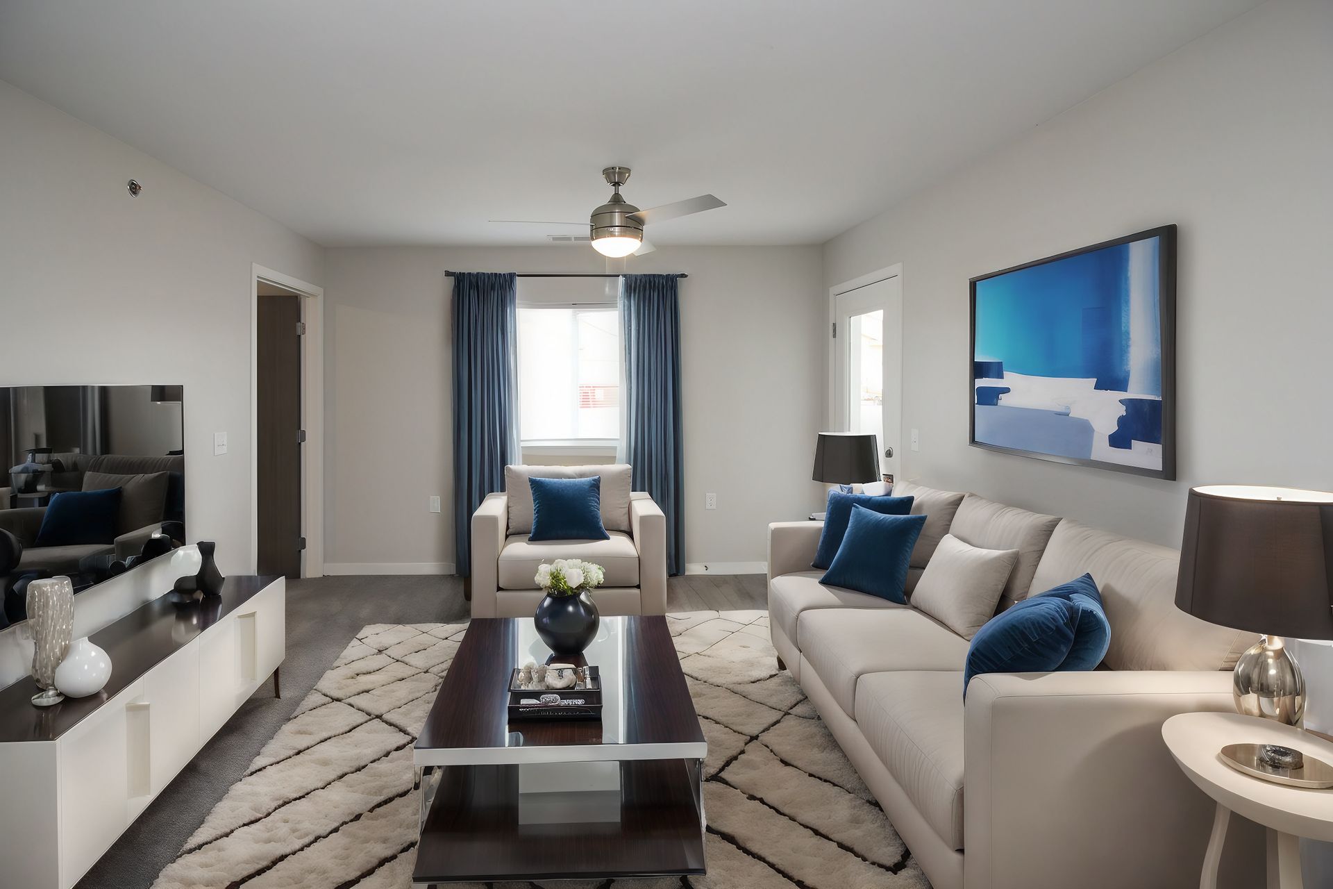 Bright modern living room with gray sofas, blue accents, wall art, and a window with curtains