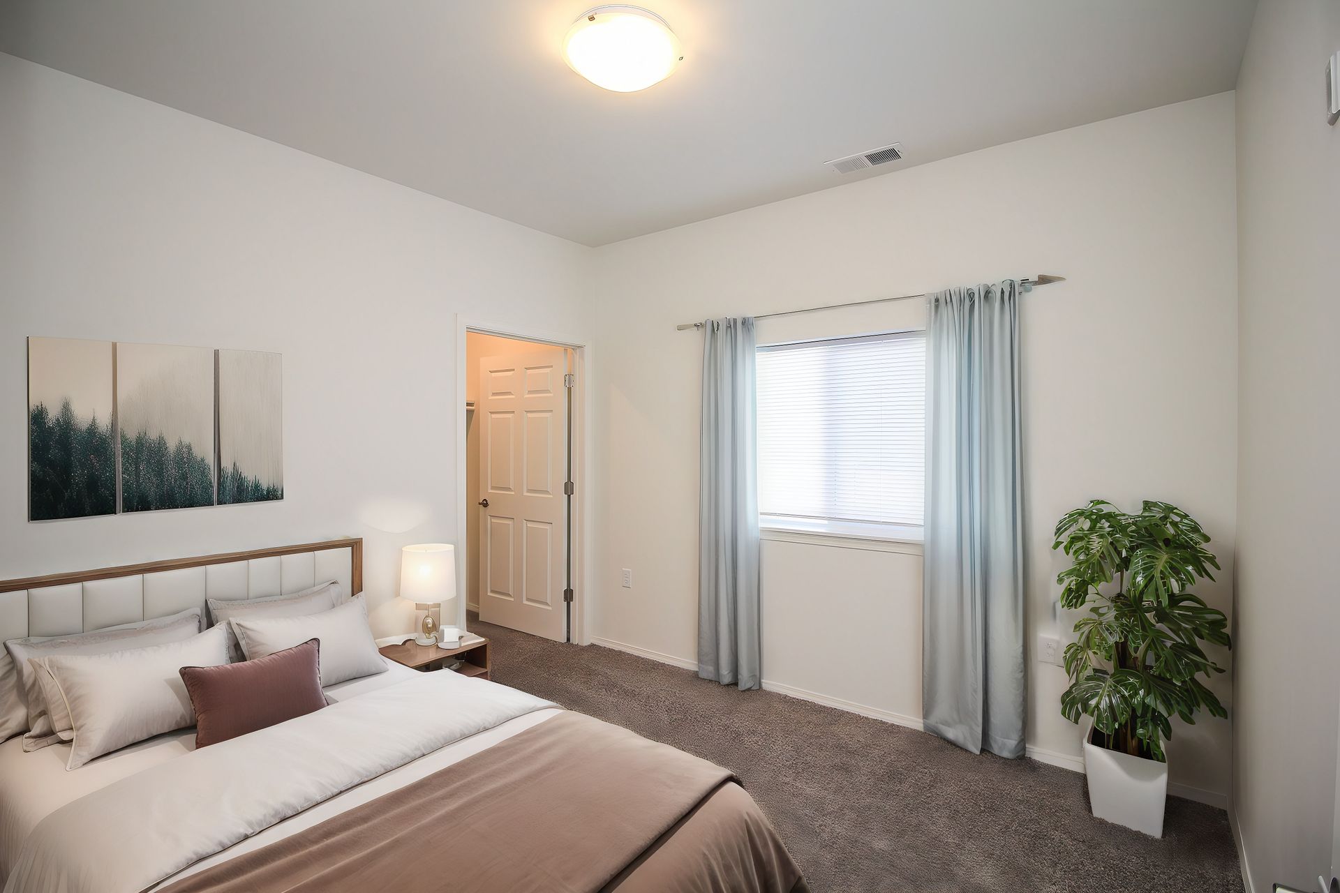 Bright bedroom with a bed, window with curtains, closet door, and a potted plant