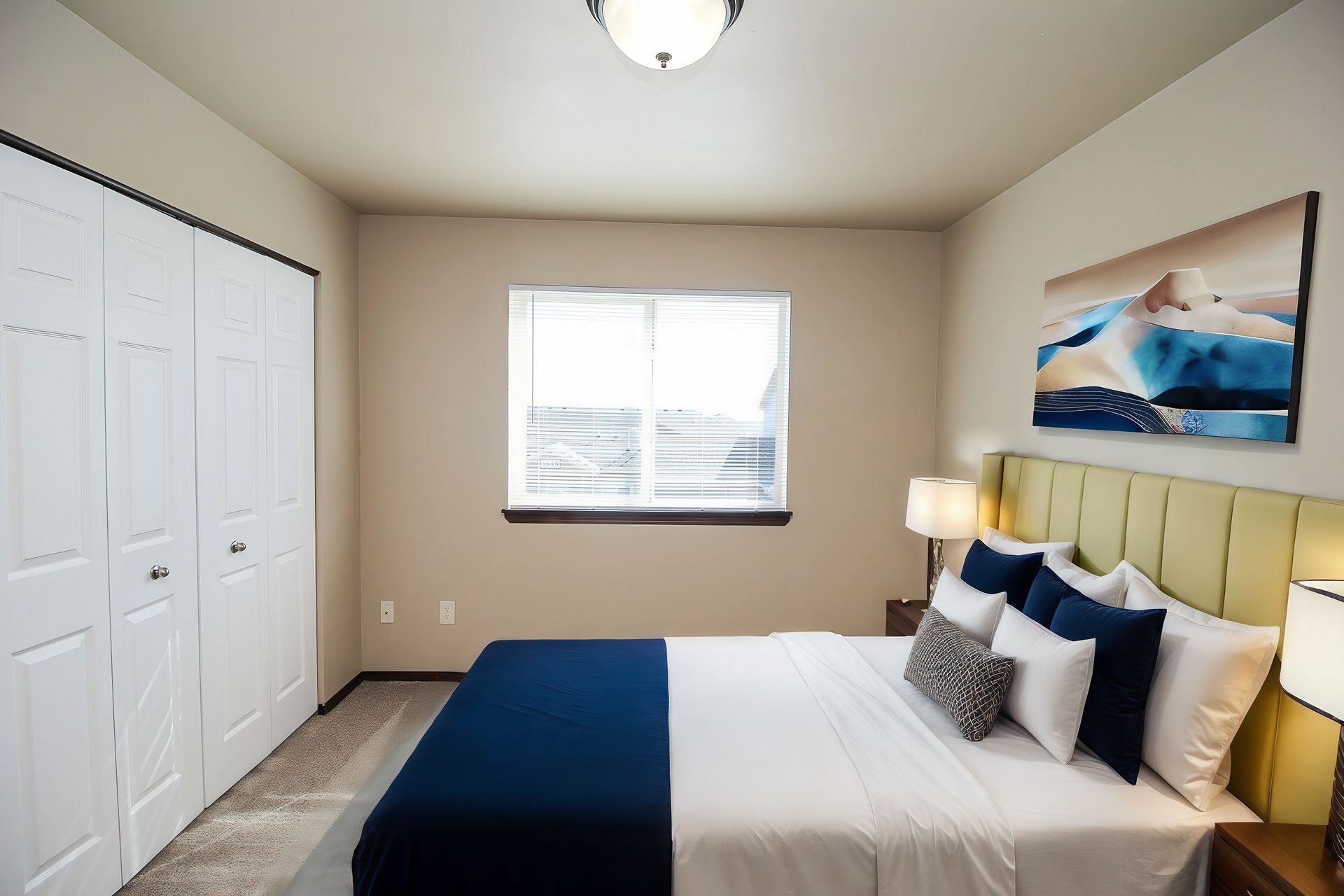 Bright bedroom with white closet, blue-and-white bed, window, and beach wall art