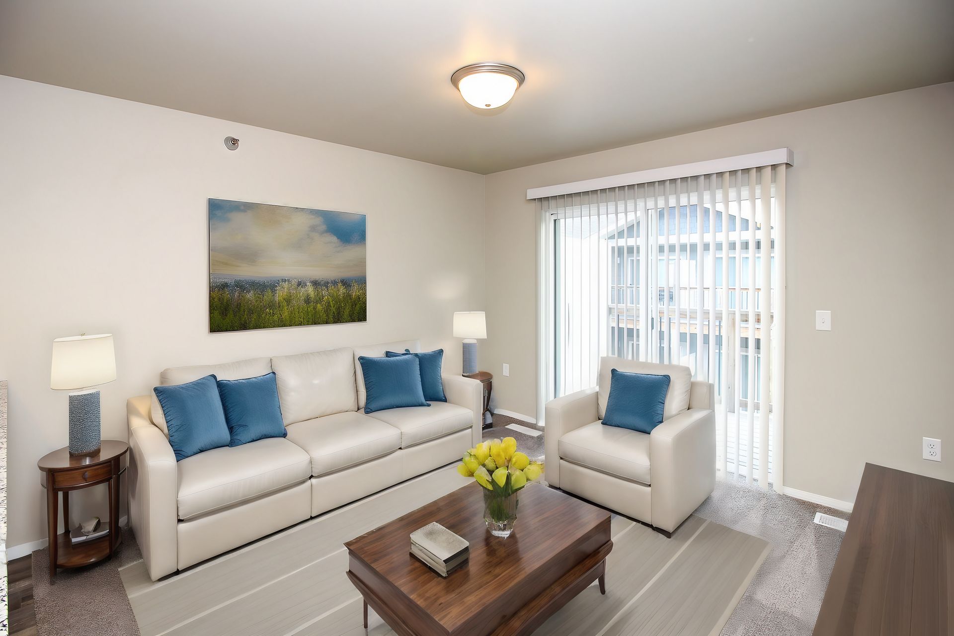 Bright living room with white sofa, blue chairs, coffee table, and sliding glass door.