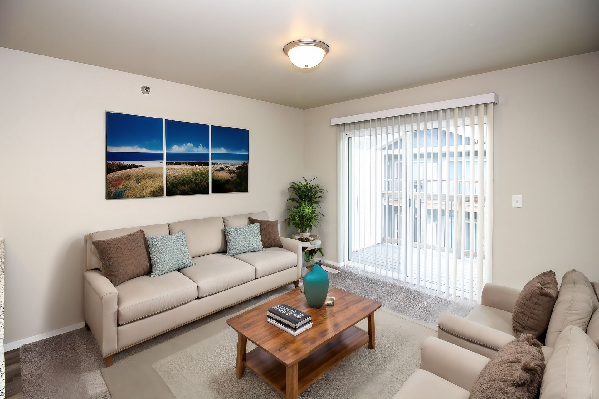 Bright living room with beige sofas, wooden coffee table, wall art, and sliding glass door to a balcony
