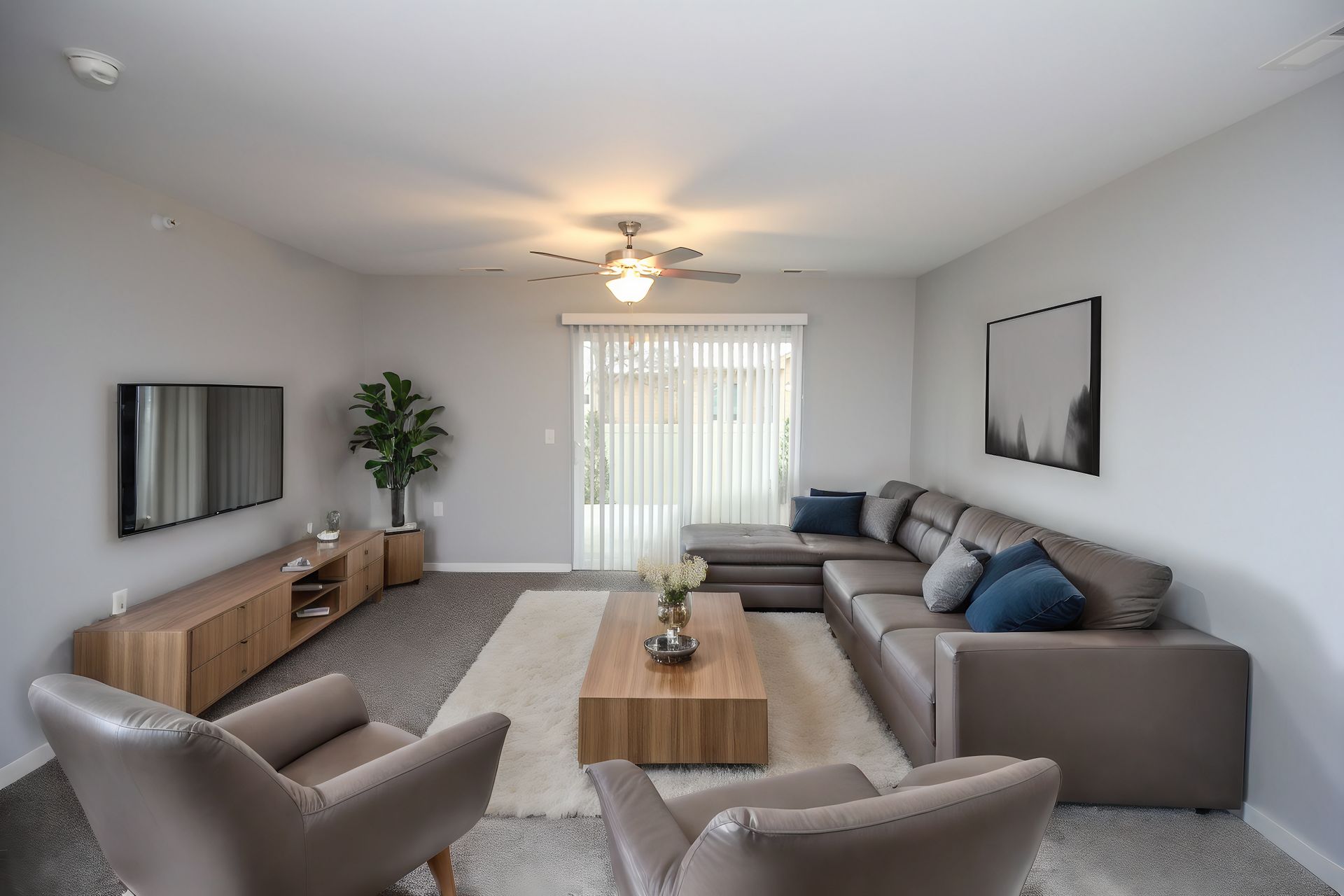 Bright modern living room with gray sofa, armchairs, coffee table, TV, and sliding glass doors