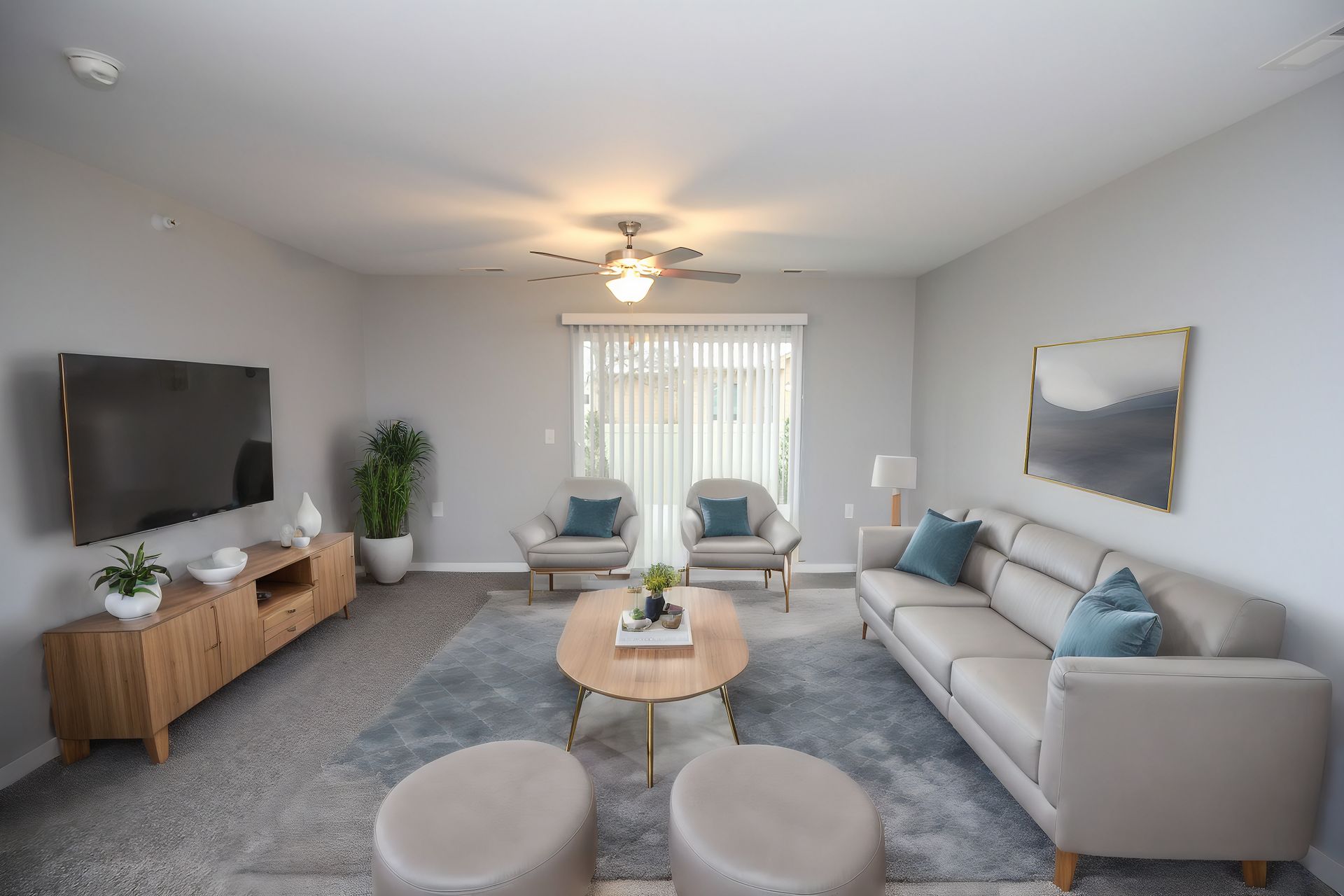Bright living room with gray sofa, wall TV, coffee table, armchairs, and blue rug near sliding doors
