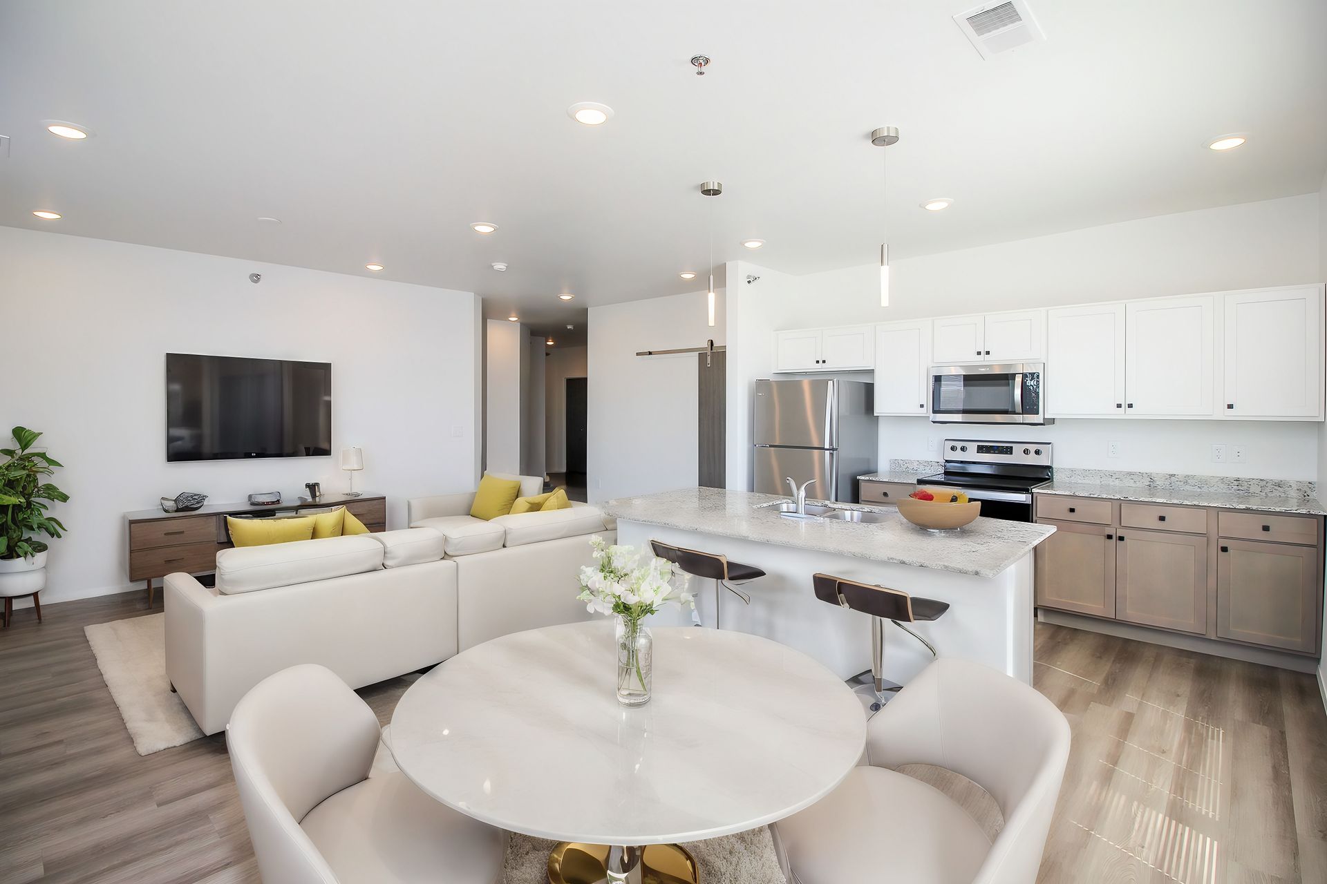 Modern kitchen with stainless steel appliances, light wood cabinets, and white countertops