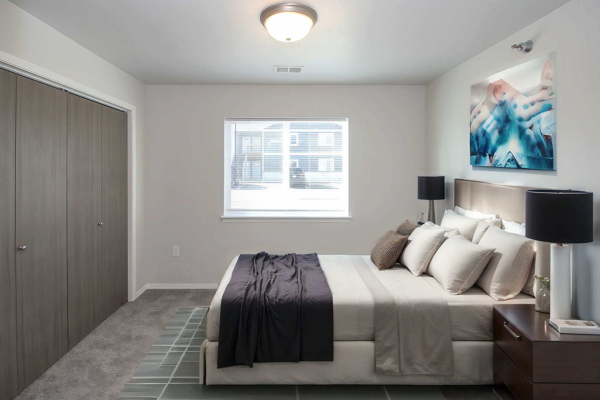 Modern bedroom with a bed, nightstands, black lamps, closet doors, and a window with blinds