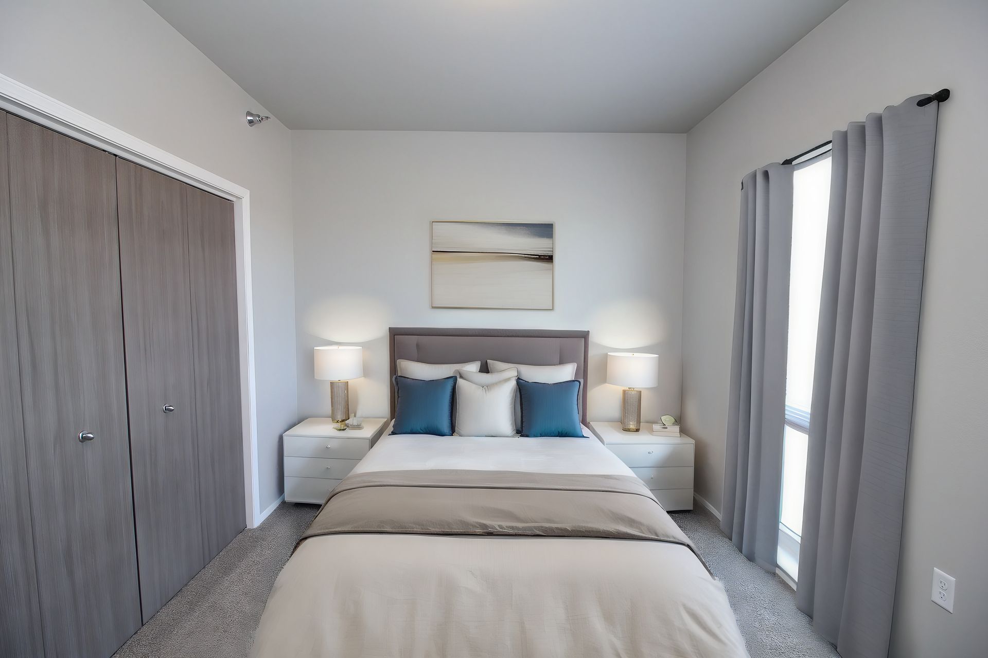 Modern bedroom with a gray bed, blue pillows, white nightstands, and closets on both sides
