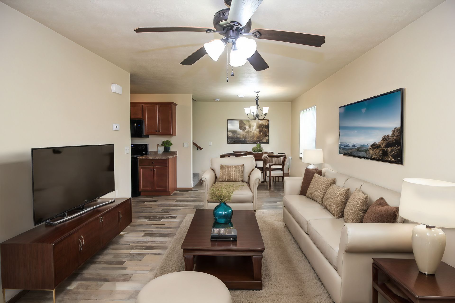 Bright living room with beige sofa, TV, coffee table, ceiling fan, and dining area in the background