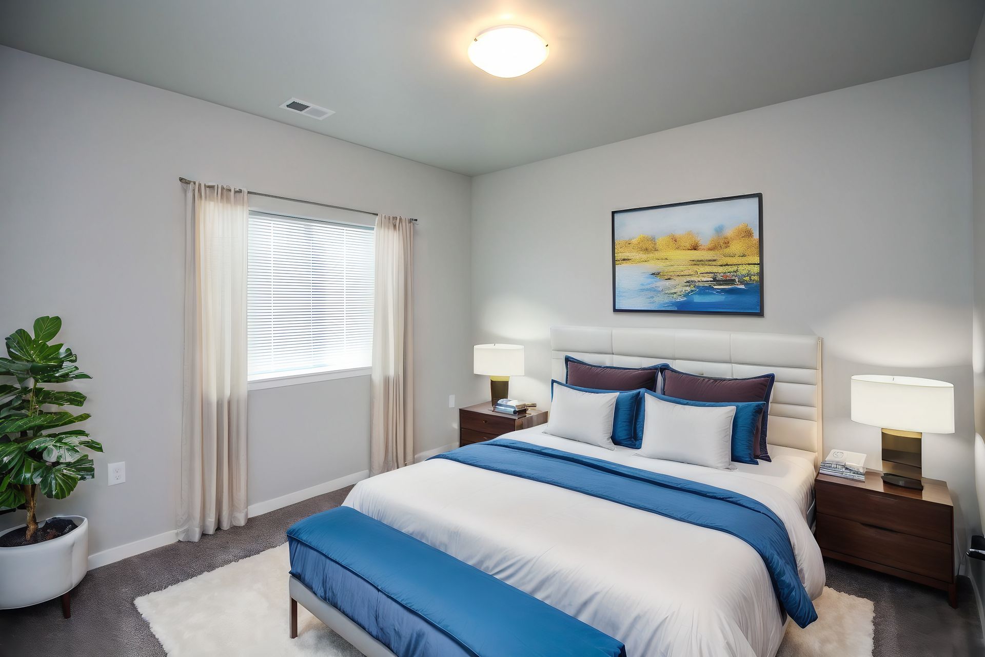 Bright bedroom with blue-striped bed, bedside lamps, window, and framed landscape art
