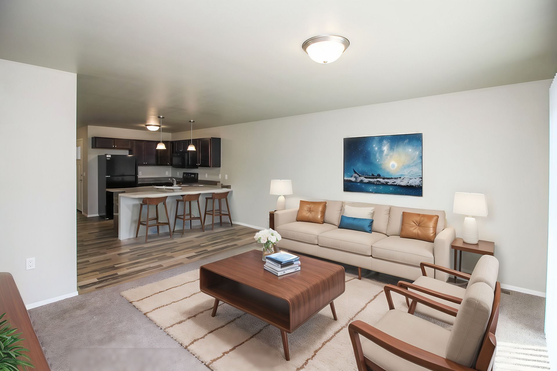 Bright living room with white sofa, wooden coffee table, armchairs, rug, and open kitchen in the background