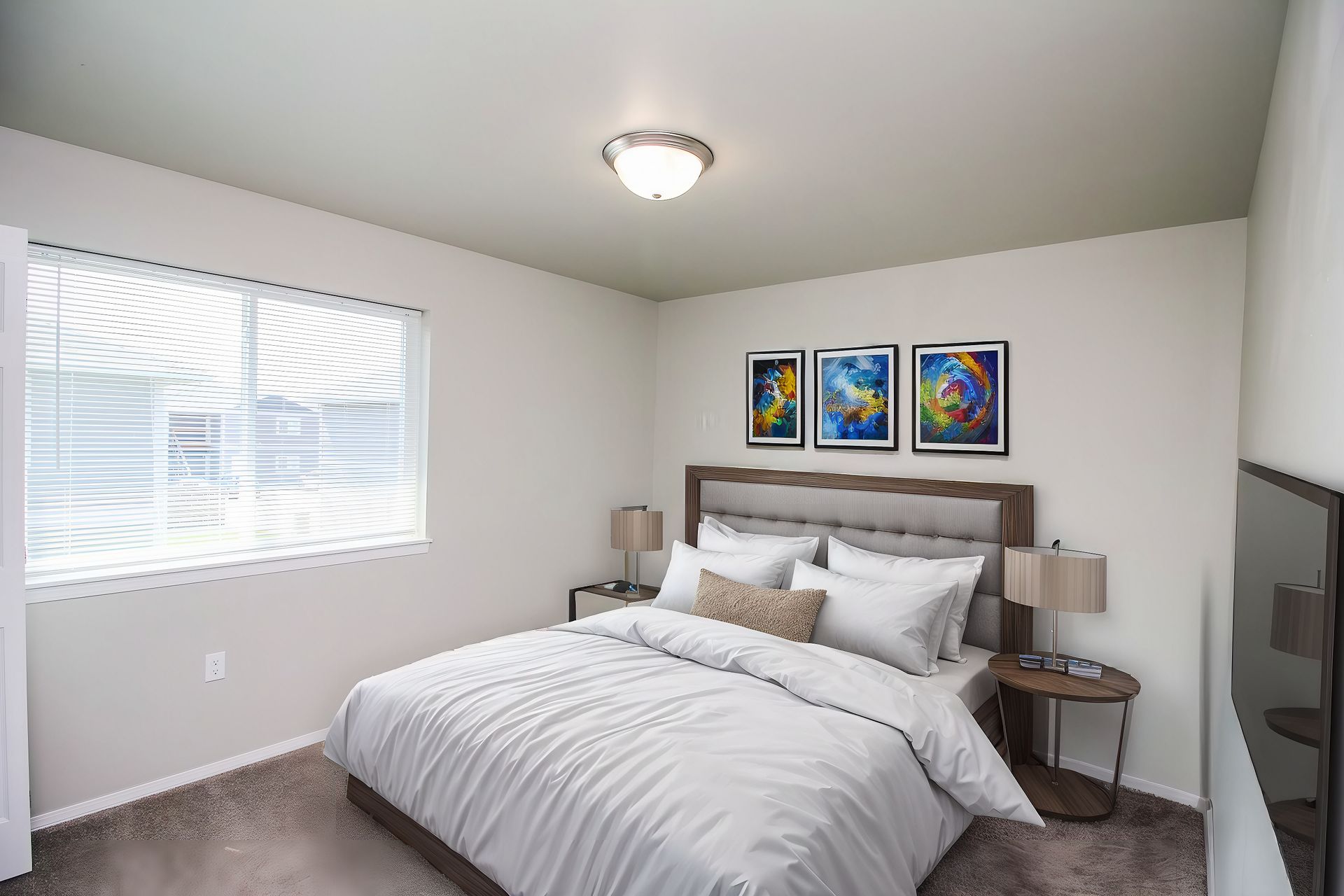 Bright bedroom with a bed, bedside tables, white walls, and colorful framed art above the headboard