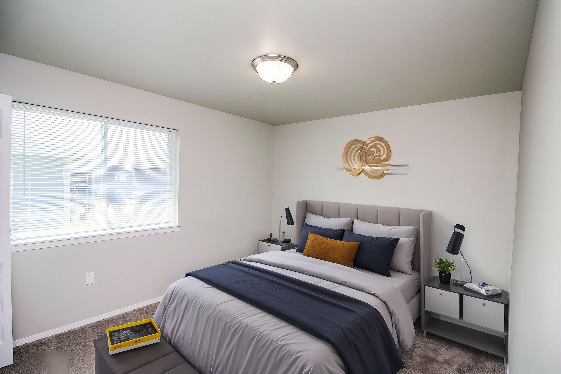 Bright bedroom with a made bed, gray walls, window, and bedside tables with lamps.
