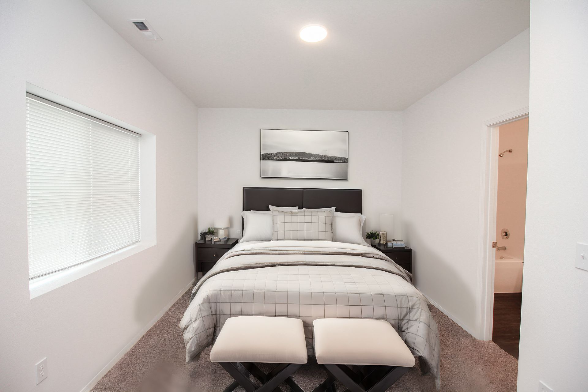 Minimal bedroom with a neatly made bed, bench at the foot, and a window on the left.