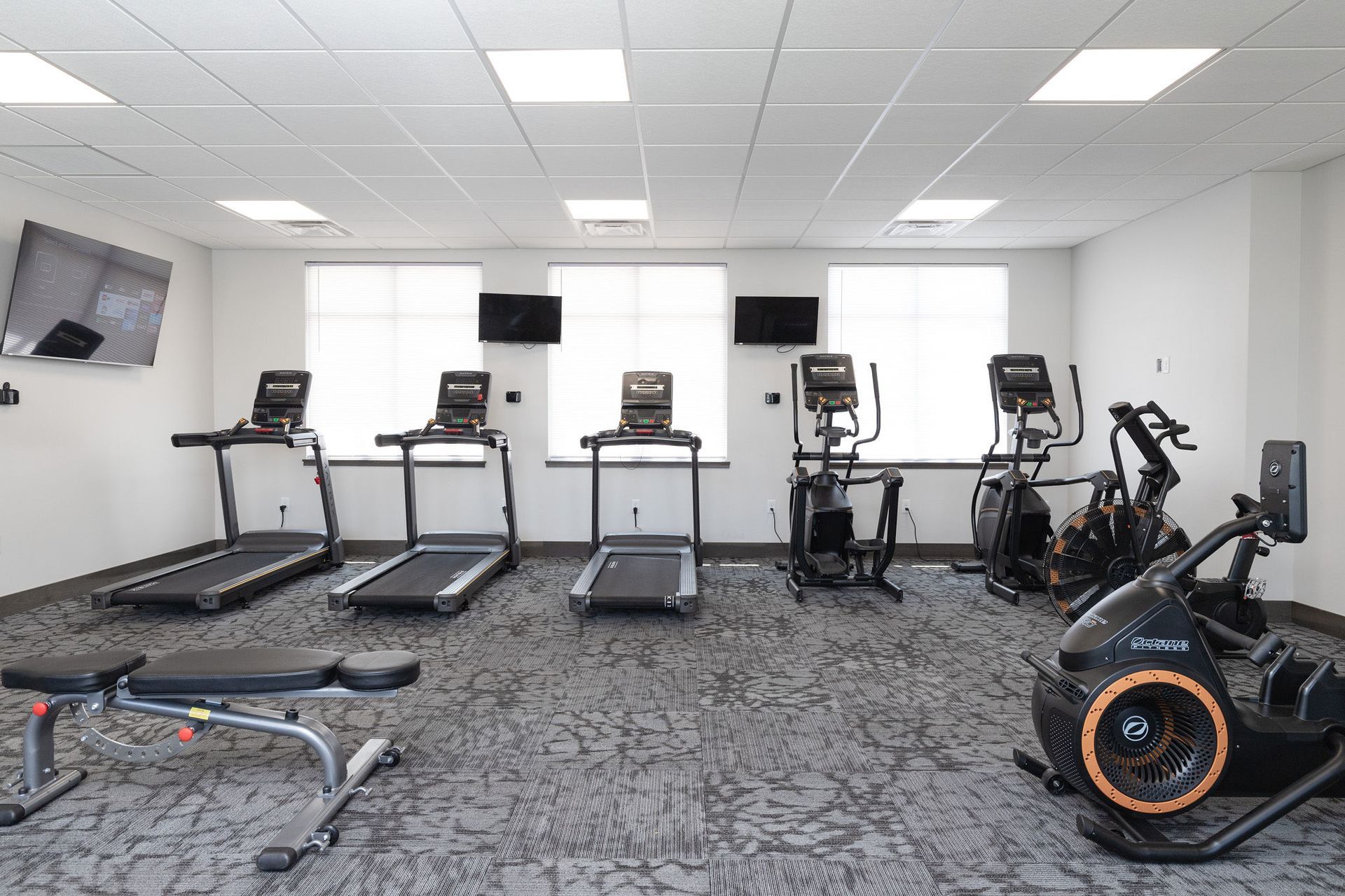 Gym with treadmills, stationary bikes, and other exercise equipment in a bright room