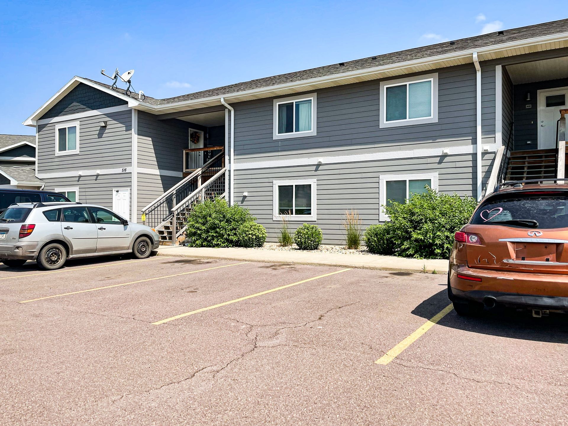 Apartment building parking lot with two cars and yellow parking lines