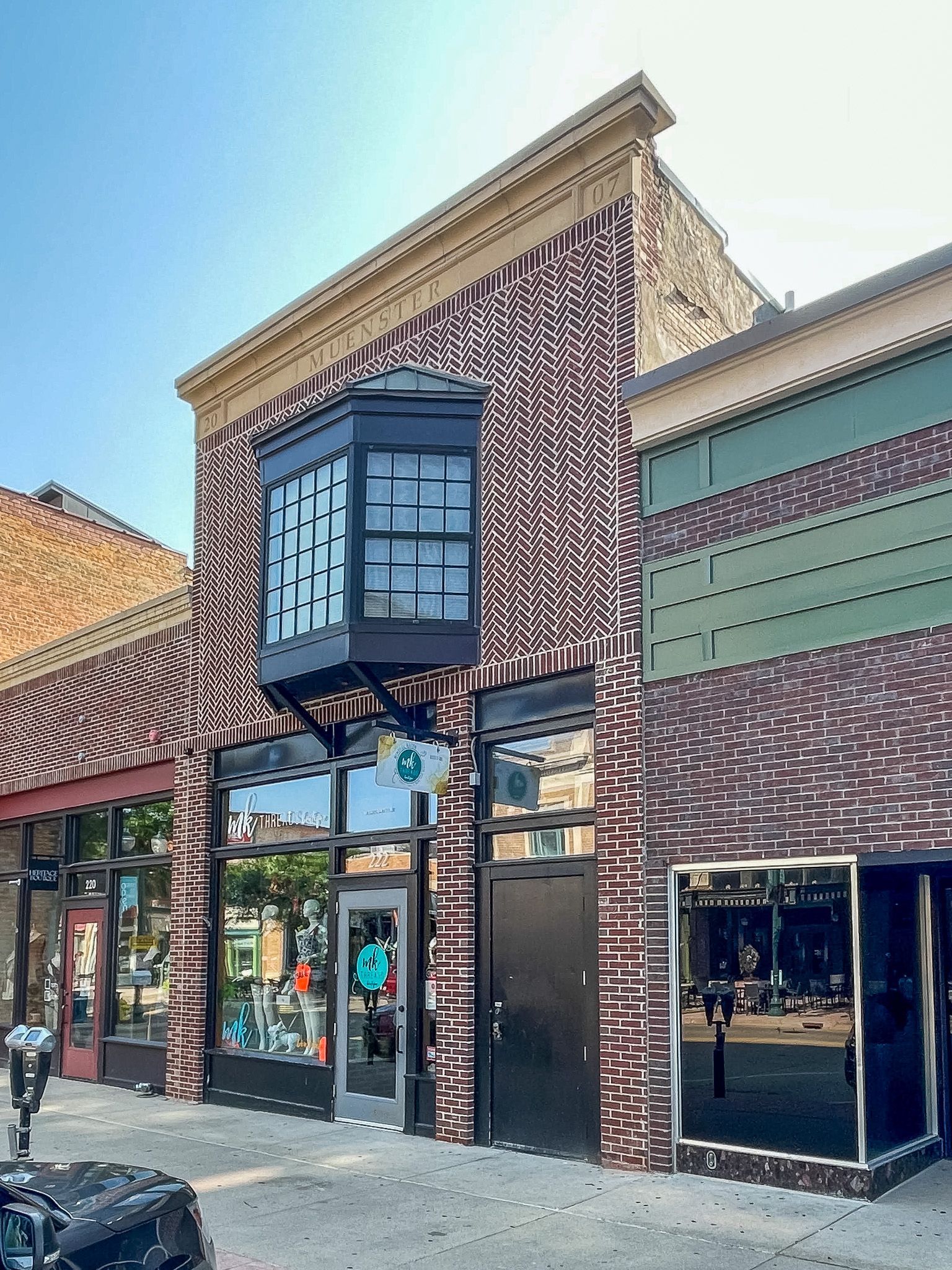 Brick storefront with arched bay window and glass doors along a sunny street