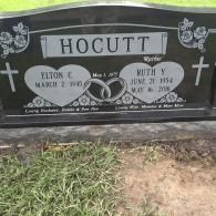 Black granite headstone for Elton C. and Ruth Y. Hocutt, featuring carved hearts, wedding rings, and floral motifs.