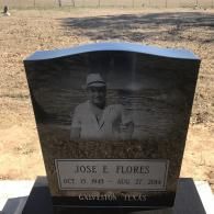 A black granite tombstone featuring an etched portrait of a person in a hat, inscribed 