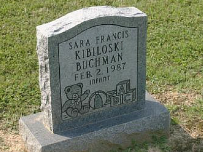 A gray granite grave marker for Sara Francis Kibiloski Buchman, dated Feb. 2, 1987, featuring engravings of toys.