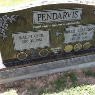 A dark granite headstone for Ralph Cecil and Billie J. Allison Pendarvis, featuring a floral design and their dates.