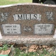 A granite headstone for the Mills family, featuring inscriptions for Johnny Ray and Sarah Eluan Moore in a cemetery.