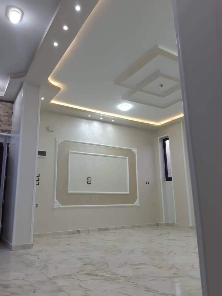 Interno moderno caratterizzato da un pannello decorativo a parete bianco e beige, pavimento effetto marmo e faretti a incasso a soffitto.