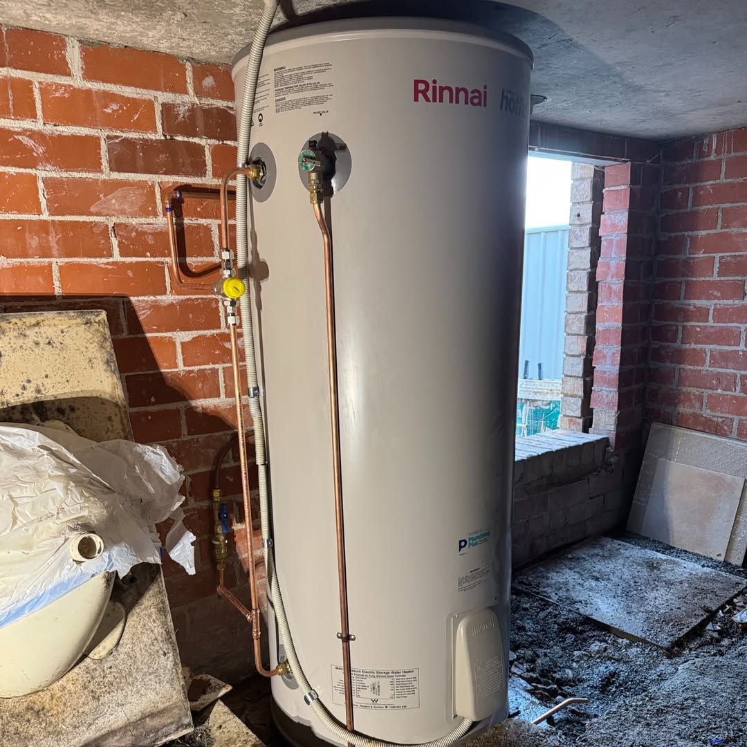 A Rinnai hot water cylinder installed against a red brick wall in Coffs Harbour by Jetty Plumbing.