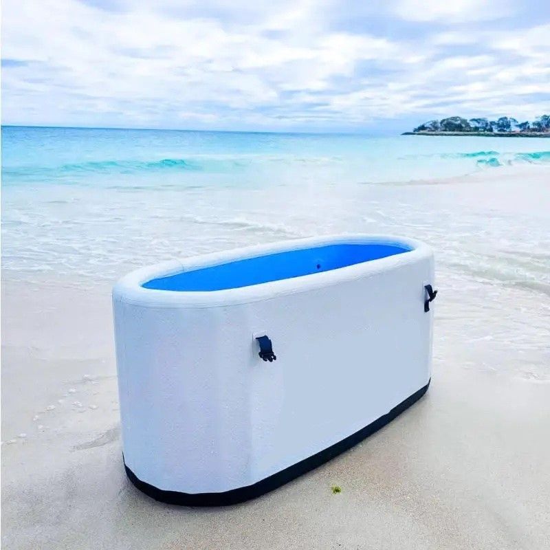 a white icebath with a blue top is on the beach