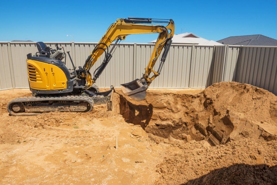 A yellow excavator is digging a hole in the ground — Bennettron Demex in Corindi Beach, NSW