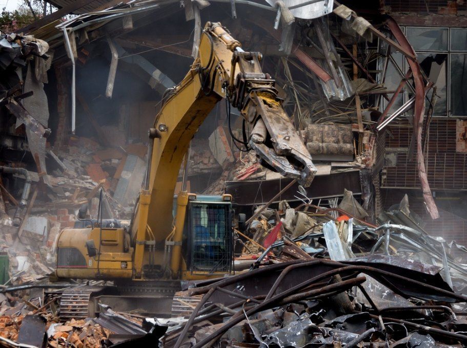 A Large Yellow Excavator is Demolishing a Building — Bennettron Demex in Gunnedah, NSW