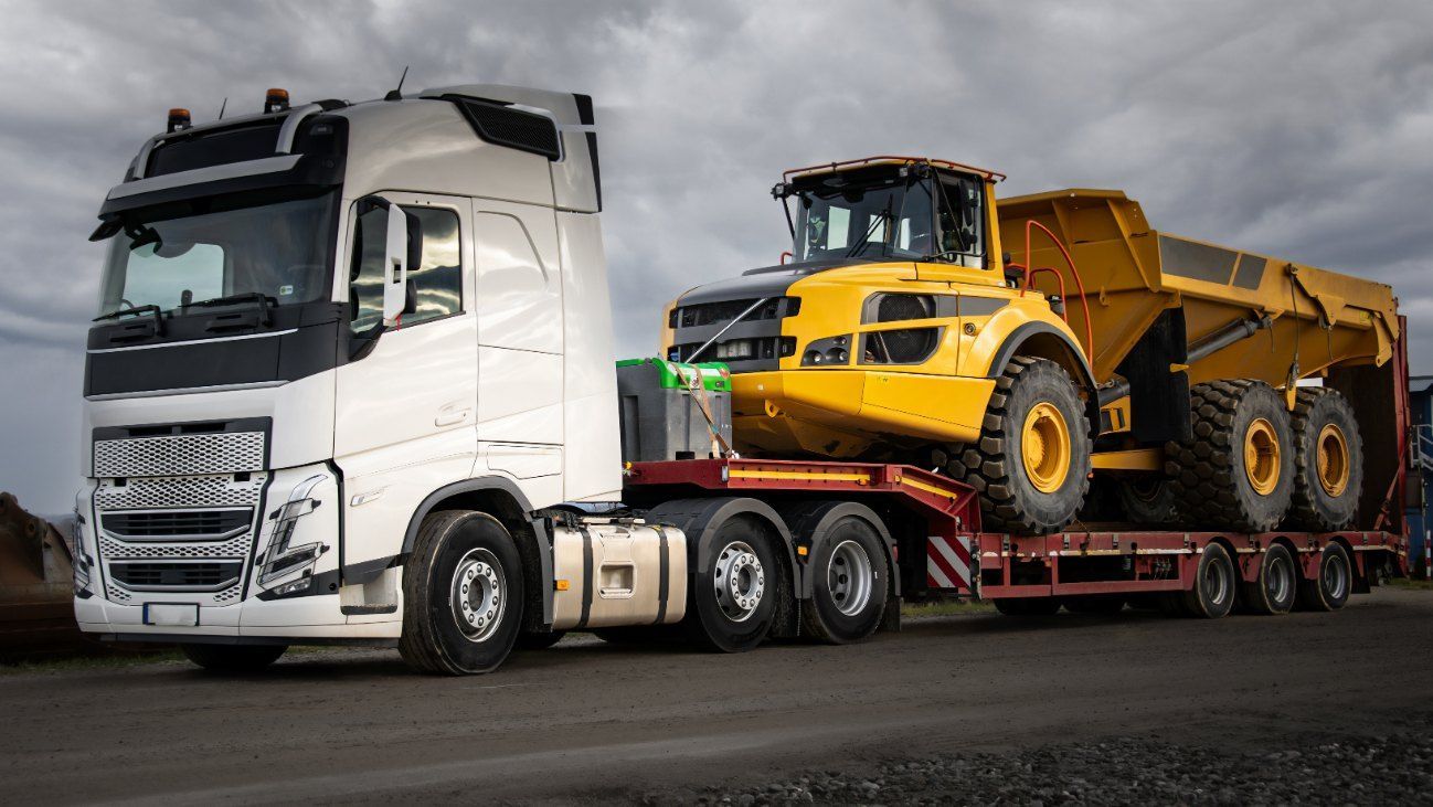 A White Truck is Carrying a Yellow Dump Truck on a Trailer — Bennettron Demex in Bonville, NSW