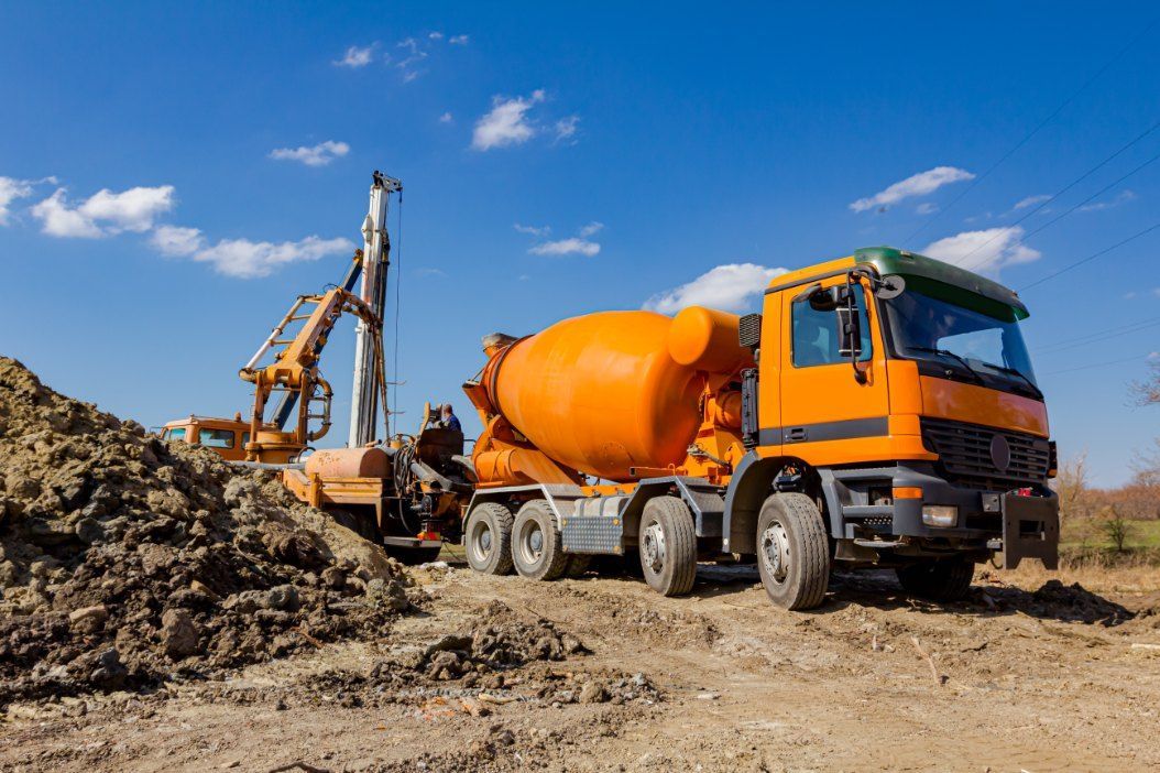 An Orange Cement Mixer Truck is Parked in a Dirt Field — Bennettron Demex in Tamworth, NSW