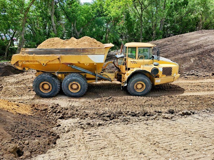 A Yellow Dump Truck is Driving Down a Dirt Road — Bennettron Demex in Kyogle, NSW