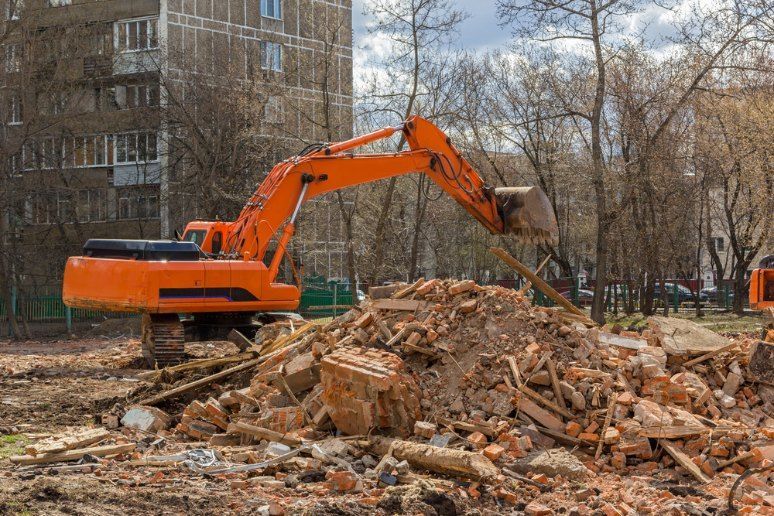 An Orange Excavator is Working on a Pile of Bricks — Bennettron Demex in Casino, NSW