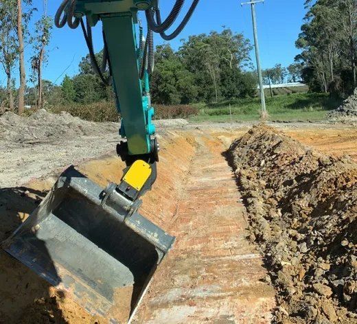 A Green and Yellow Excavator is Digging a Hole in the Dirt — Bennettron Demex in Inverell, NSW
