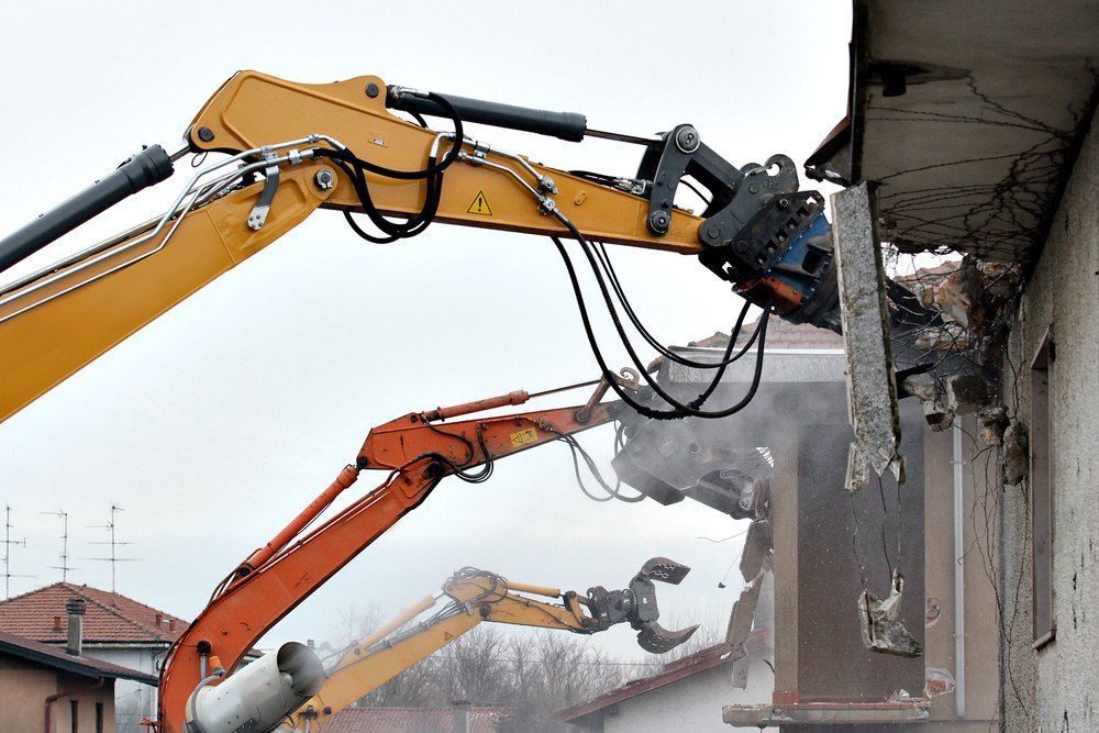 A Yellow and Orange Excavator is Demolishing a Building — Bennettron Demex in Port Macquarie, NSW
