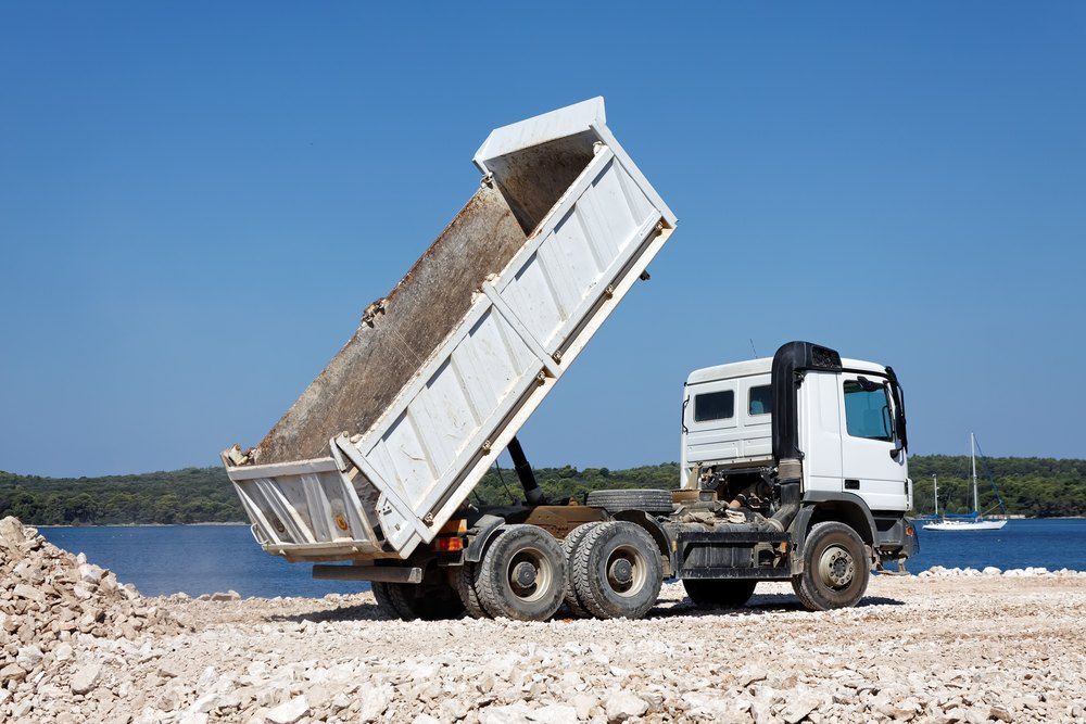 A Dump Truck is Sitting on a Rocky Beach Next to a Body of Water — Bennettron Demex in Grafton, NSW