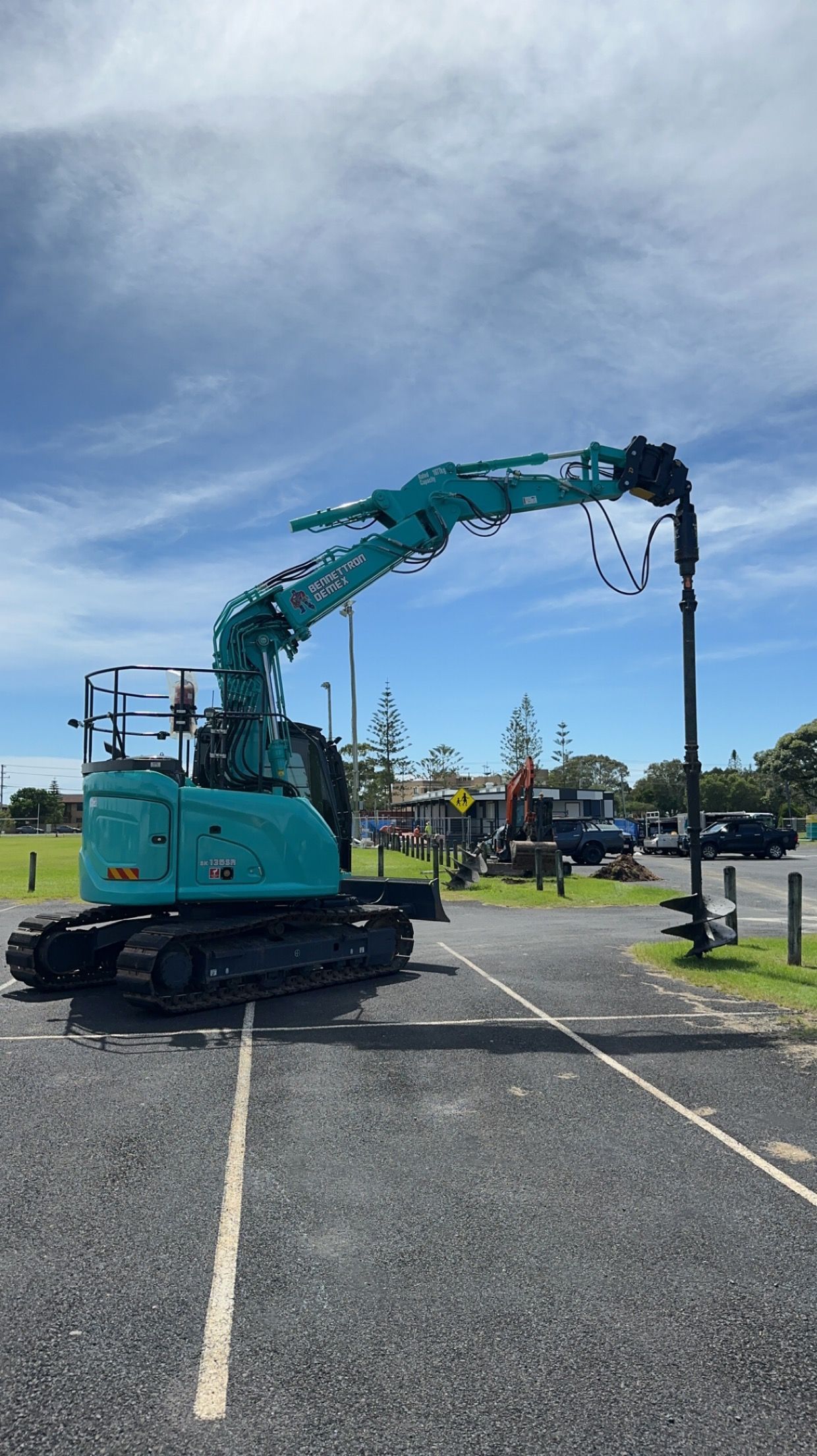 A Large blue digger is carrying drill while parked in carpark — Bennettron Demex in Corindi Beach, NSW