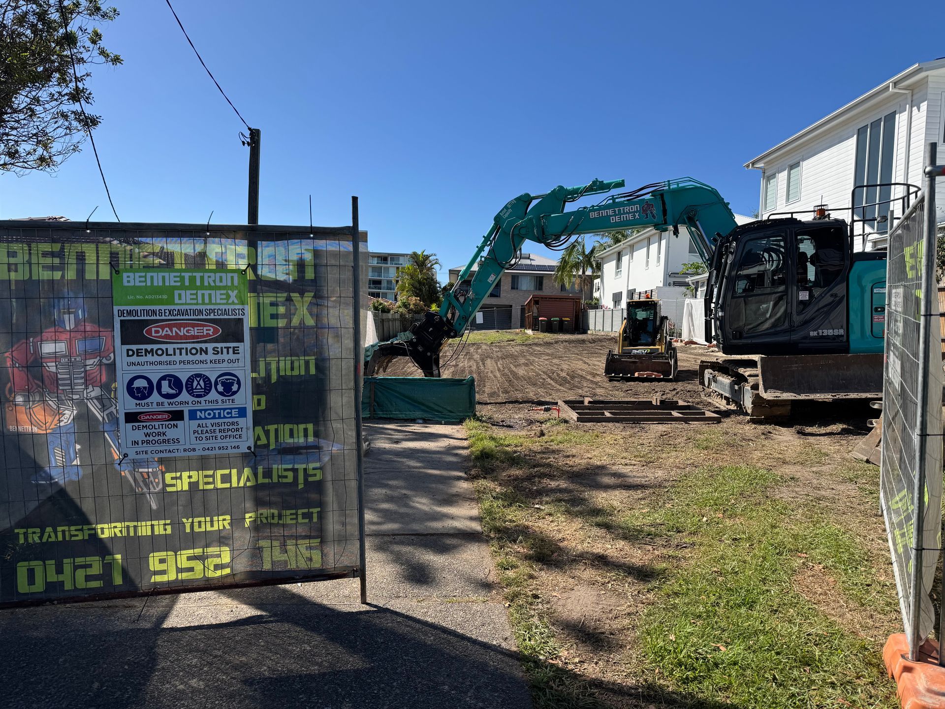 A digger and small tractor are on empty lot of dirt with fence captured in image — Bennettron Demex in Corindi Beach, NSW