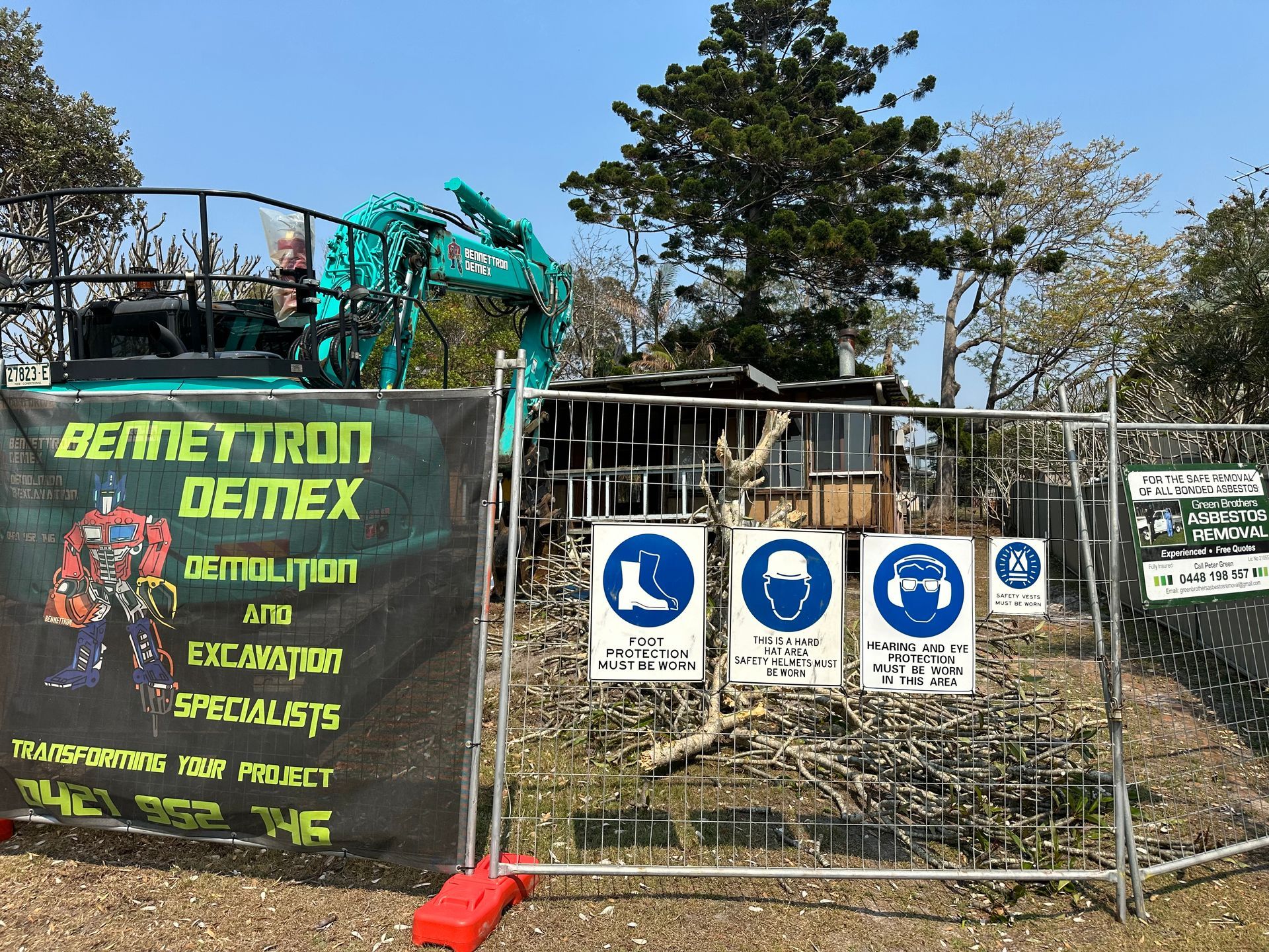 A property is sectioned off with fencing while house is being demolished with trees in background — Bennettron Demex in Corindi Beach, NSW