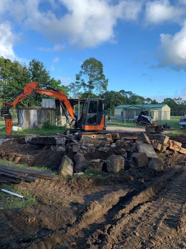 An Excavator is Digging a Hole in the Dirt in Front of a House — Bennettron Demex in Tenterfield, NSW