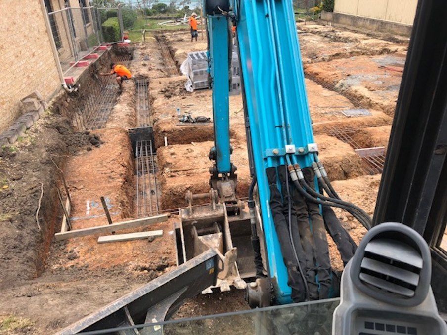A Blue Excavator is Digging a Hole in the Dirt on a Construction Site — Bennettron Demex in Armidale, NSW