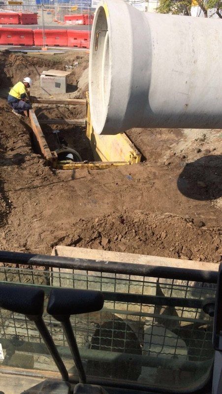 A Man is Sitting in the Dirt Next to a Large Pipe — Bennettron Demex in Bellingen, NSW