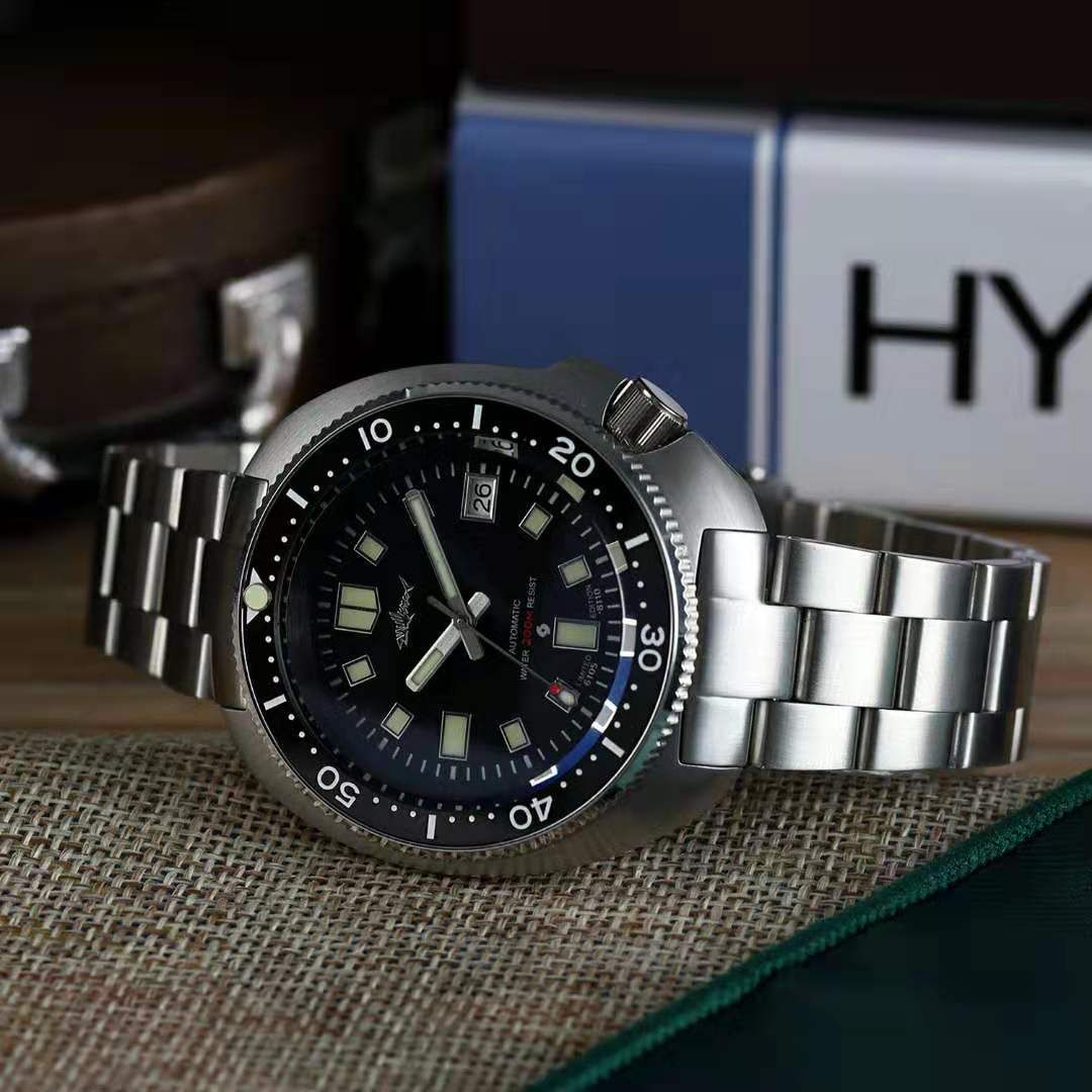 A watch is sitting on a table next to a book.