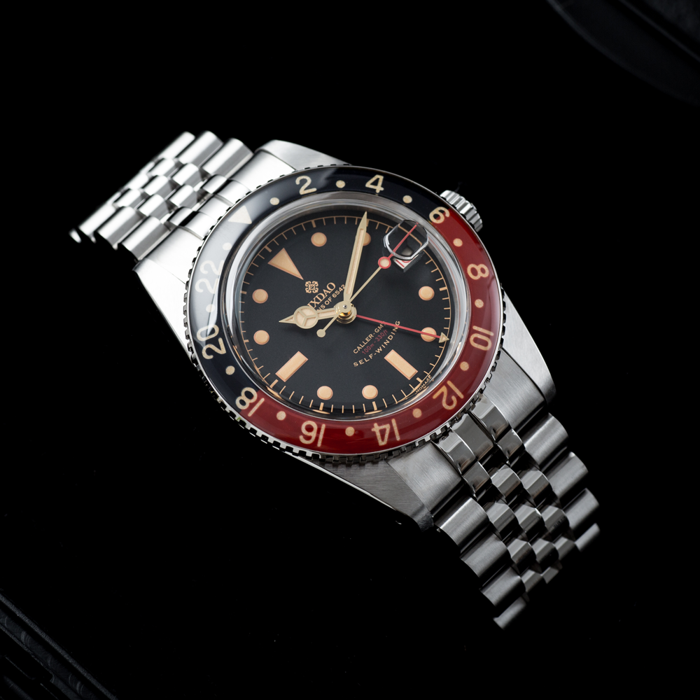 A silver rolex watch with a red and black face