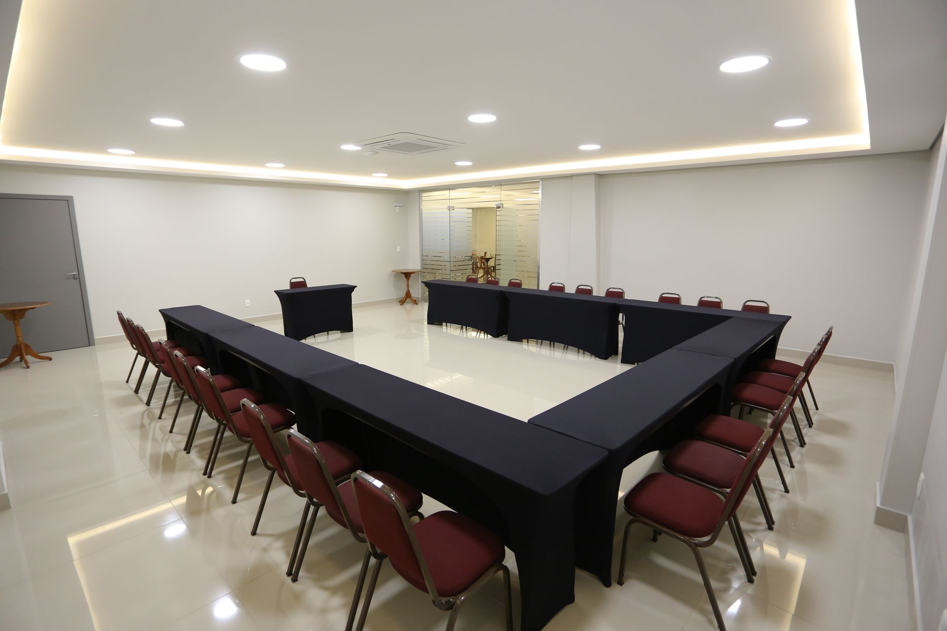 Sala de conferências com fileiras de mesas e cadeiras, toalhas de mesa azuis.