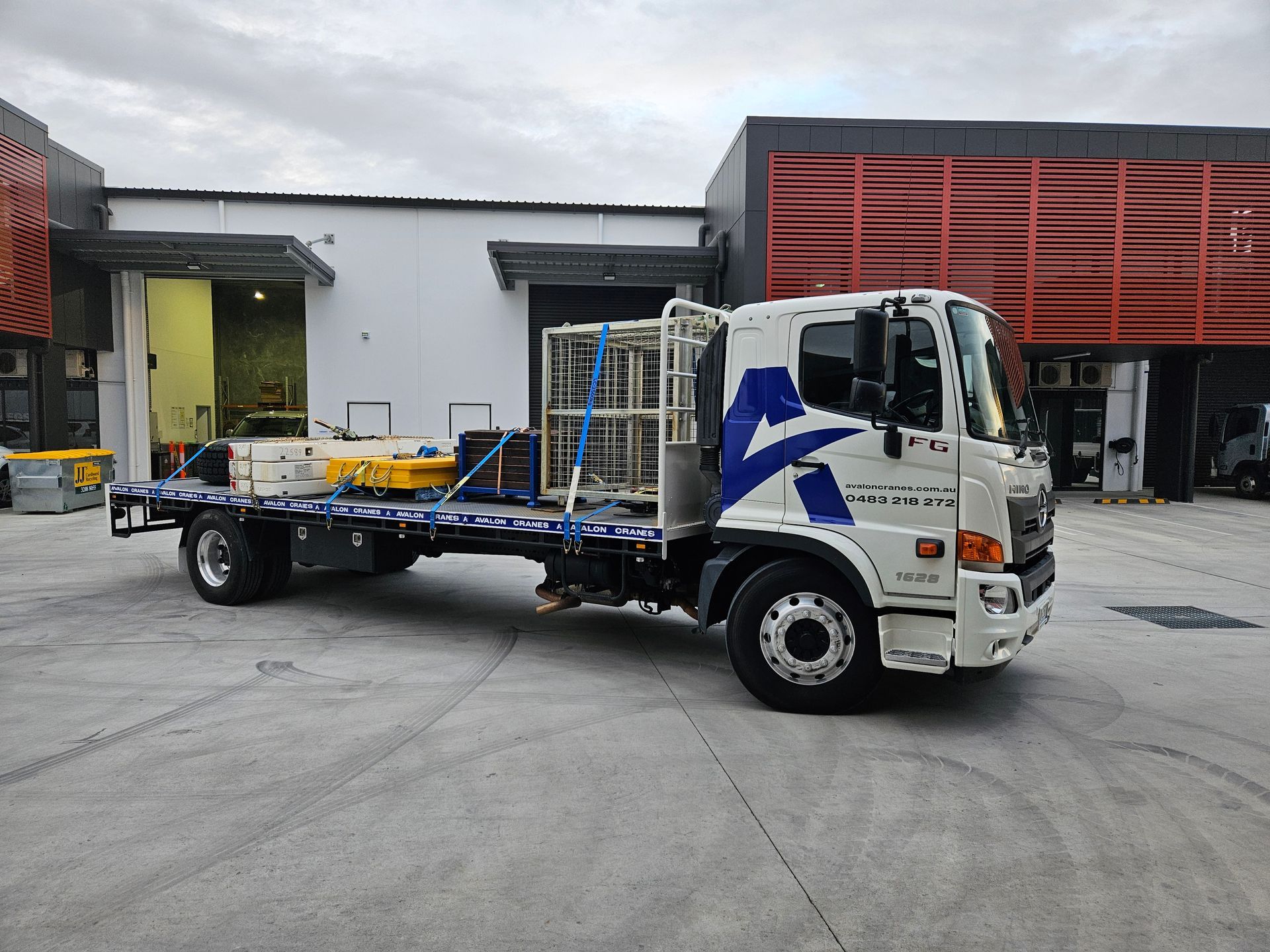 A white truck with a blue crane on the back is parked in a parking lot.